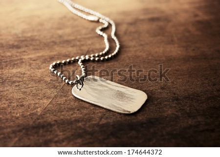 Blank silver tag on a ball chain, on a old wooden desk.  