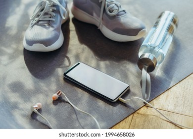 Blank Smartphone Screen With Earphones, Bottle With Water And Sneakers On The Background. Set For Running And Sports Activities . Healthy And Active Lifestyle. Online Workout. Fitness App Mockup.