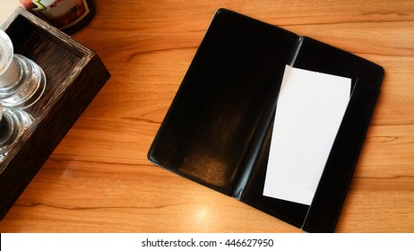 Blank Space Of Black Leather Restaurant Bill Receipt Holder On Table

