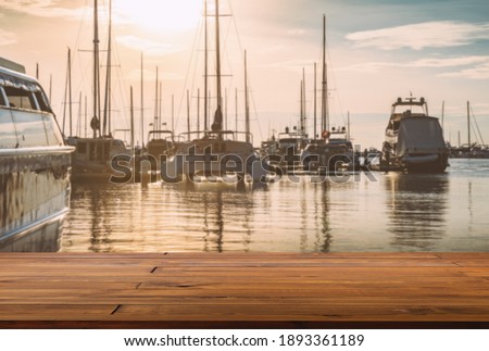 Blank space of wooden plank floor at marina, blurred background of sea, yachts and sunset sky. Warming looks view of yacht dock.
