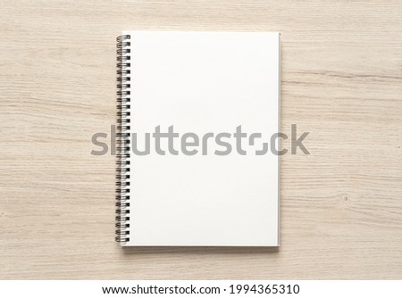 Blank spiral bound notepad mockup template on wood background. High resolution.