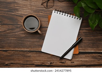 Blank spiral notebook, glasses and cup of coffee on wooden table. Top view - Powered by Shutterstock