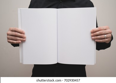 Blank spread, open book in man's hands - Shutterstock ID 702930457