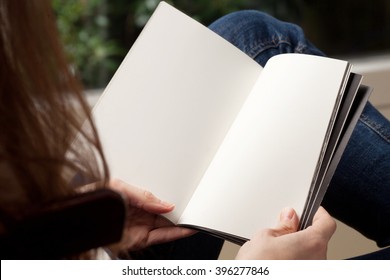 Blank spread, open book in woman's hands 
