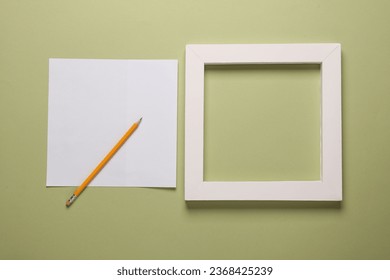 Blank square frame with white sheet of paper and pencil on green background