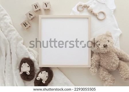 Blank square wooden frame mockup for nursery art or pregnancy announcement display, flat lay with baby toys and accessories.