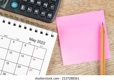 Blank sticky note on May 2022 desk calendar on wooden background for your text.