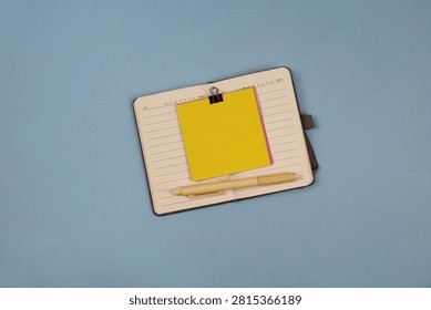 Blank sticky note on an open notebook with pen on an blue background, business planning concept with copy space.