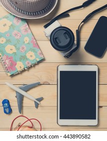 Blank tablet screen with travel objects on wooden background
