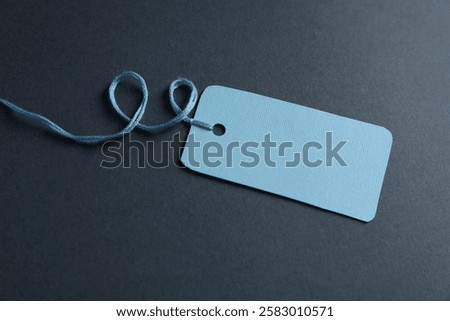 Blank tag with string on grey background, closeup