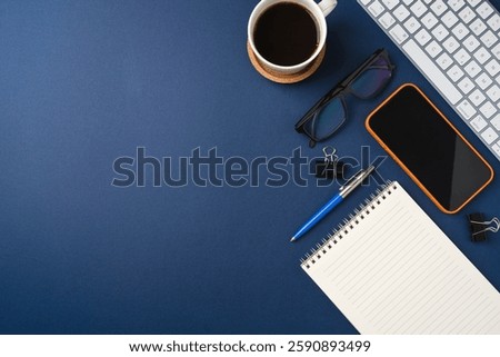 Blank touchscreen smartphone and keyboard on dark blue desk