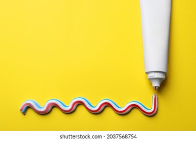 Blank tube with squeezed out toothpaste on yellow background, flat lay. Space for text