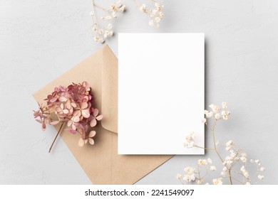 Blank wedding invitation card mockup with dried flowers on grey background. Flat lay, top view, copy space