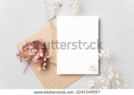 Blank wedding invitation card mockup with dried flowers on grey background. Flat lay, top view, copy space