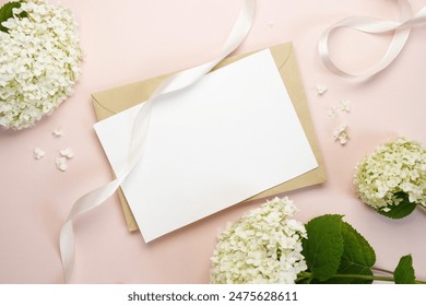 Blank wedding invitation or greeting card mockup with white hydrangea flowers on a beige background. Flat lay, top view, copy space. - Powered by Shutterstock - Get 15% off with code: PIKWIZARD15