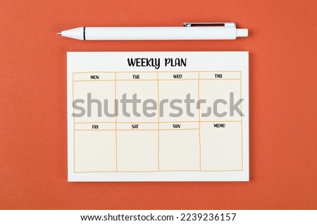 Blank weekly plan notice block on orange colour background. Empty schedule and a pen.