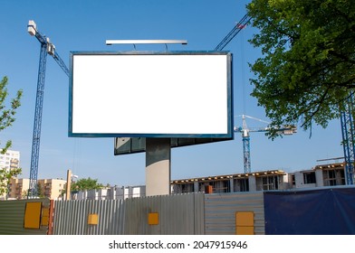 Blank White Billboard For Advertisement In Front Of The Construction Site. Apartment Building Under Construction On A Sunny Day.