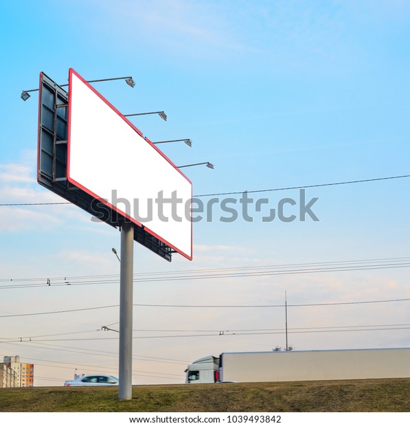 Blank white\
billboard on the highway with passing cars on the background of\
multi-storey city buildings, mock\
up