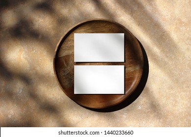 Blank white business cards mockups on wooden plate. Marble backgound with palm leaf shadow overlay. Modern template for branding identity. Tropical summer, vacation design. Flat lay, top view. 
