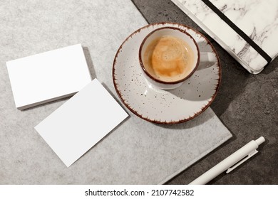 Blank white business cards on table, with cup of coffee, pen and notebook. Mockup for branding identity. Possibility to show both sides of card. Template for graphic designers. Free space, copy space.