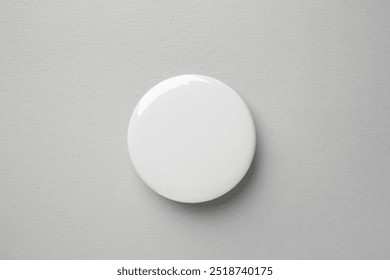 Blank white button badge on grey background, top view. Mockup for design