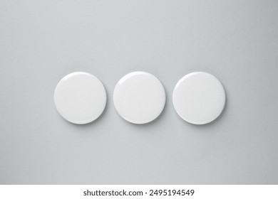 Blank white button badges on grey background, top view. Mockup for design