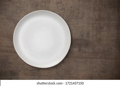 Blank White Ceramic Round Dish On Wooden Desk Blackground With Copy Space, Flat Lay Of Traditional Handcrafted Kitchenware Concept