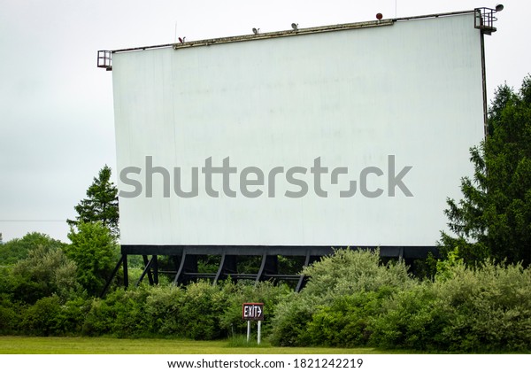 Blank\
white drive-in movie screen; rural outdoor\
setting