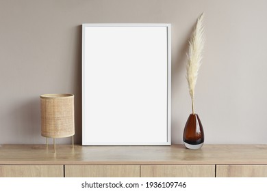 Blank white empty picture frame mockup on grey wall. Copy space. Artwork showcase. View of modern scandinavian style interior with chair. Home staging and minimalism concept