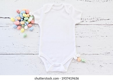 Blank white flat lay newborn  bodysuit on white wood background with easter props, baby bodysuit easter mockup