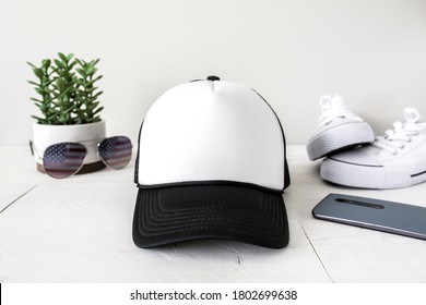 Blank white foam and black mesh trucker hat on white background with gender neutral props, baseball cap mockup