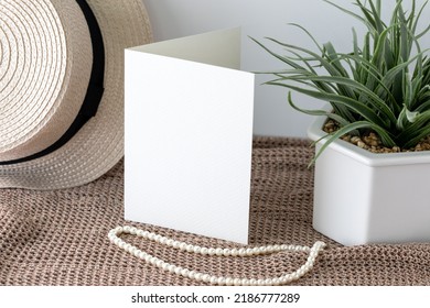 Blank White Invitation Card In Vertical Lay On Knitted Cloth With Beach Hat And Pearl Lace.