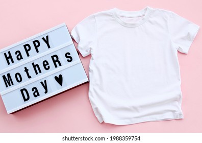 Blank White Kids Shirt With Led Light Box On 
Pink Floor. Mothers Day Toddler Shirt Model Mock Up