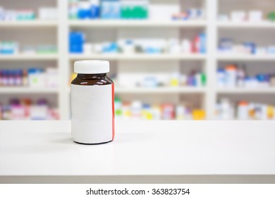 Blank white label medicine bottle on counter with blur shelves of drug in the pharmacy drugstore