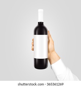 Blank White Label Mock Up On Black Bottle Of Red Wine In Hand Isolated. Alcohol Bottle Mockup Presentation Ready For Logo Design. Full Drink Bottle Holder Template Empty Sticker. Clear Tag Vine Bottle