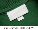 Blank white laundry care clothes label on green shirt fabric texture background