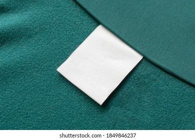 Blank White Laundry Care Clothes Label On Green Fabric Texture Background