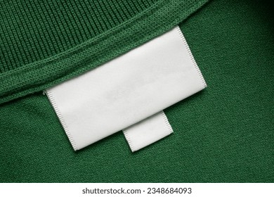 Blank white laundry care clothes label on green shirt fabric texture background