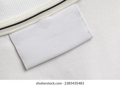 Blank white laundry care clothes label on white shirt fabric texture background