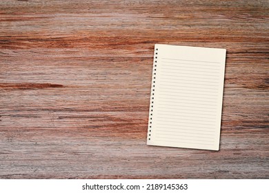 Blank White Notebook Pad On Wood Desk Background With Copy Space. Top Down