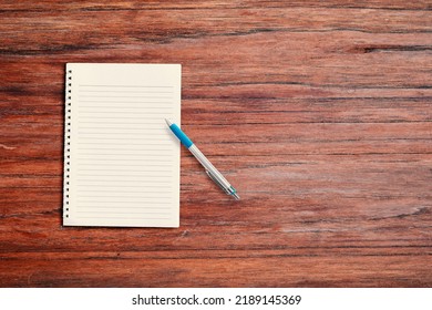 Blank White Notebook Pad On Wood Desk Background With Copy Space. Top Down