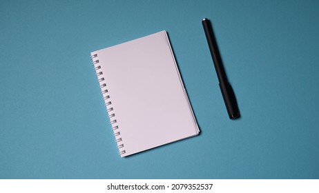 Blank, White Notebook And Pen On A Turquoise Solid Background. Notebook, Notebook For Notes.
