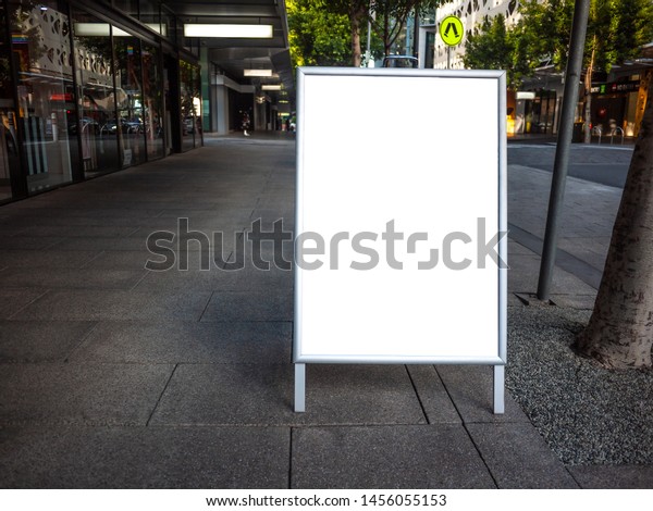 Blank white\
outdoor advertising stand/sandwich board mock up template.\
Background texture of clear street signage board placed outdoor on\
pedestrian sidewalk. Urban city\
environment.