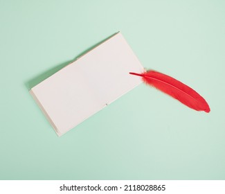 Blank White Page Ready For Writing Love Note With Red Feather On Pastel Mint Green Background.  Minimal Valentines Concept With Copy Space. Message For Loved Ones.