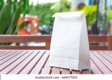 Blank White Paper Bag For Taking Away Food On A Wooden Table