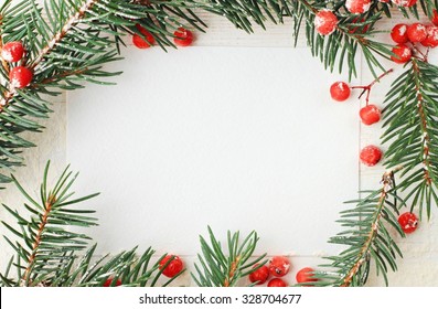 Blank white paper card framed with natural fir tree branches decor and bright red berries, wintry New Year congratulation message.  - Powered by Shutterstock