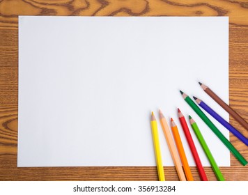 Blank White Paper And Color Pencil On Wooden Table