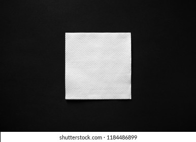 Blank white paper napkin on black background with copy space. Flat lay.