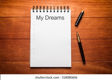 blank white paper of note book with black ink pen on wooden table, list of dreams