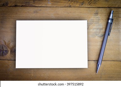 Blank White Paper With Pen On A Wooden Desk